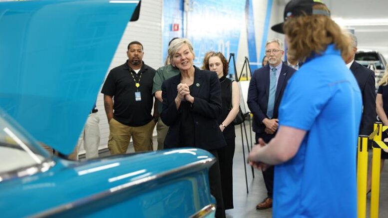 U.S. Energy Secretary Jennifer Granholm stands near the open hood of a car while talking with a student.